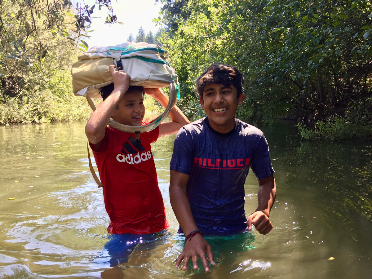 Scouts navigating through a lush forest by a river