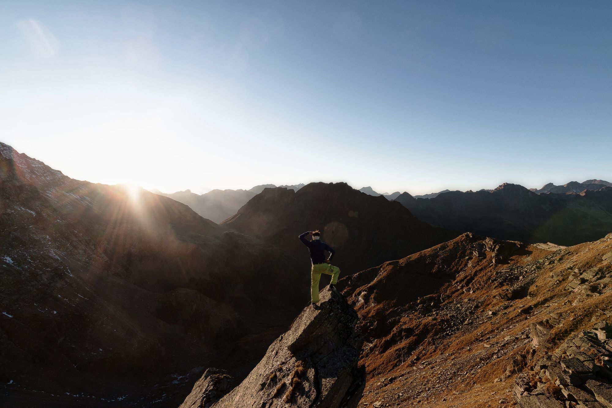 Hiker standing on a mountain peak at sunrise