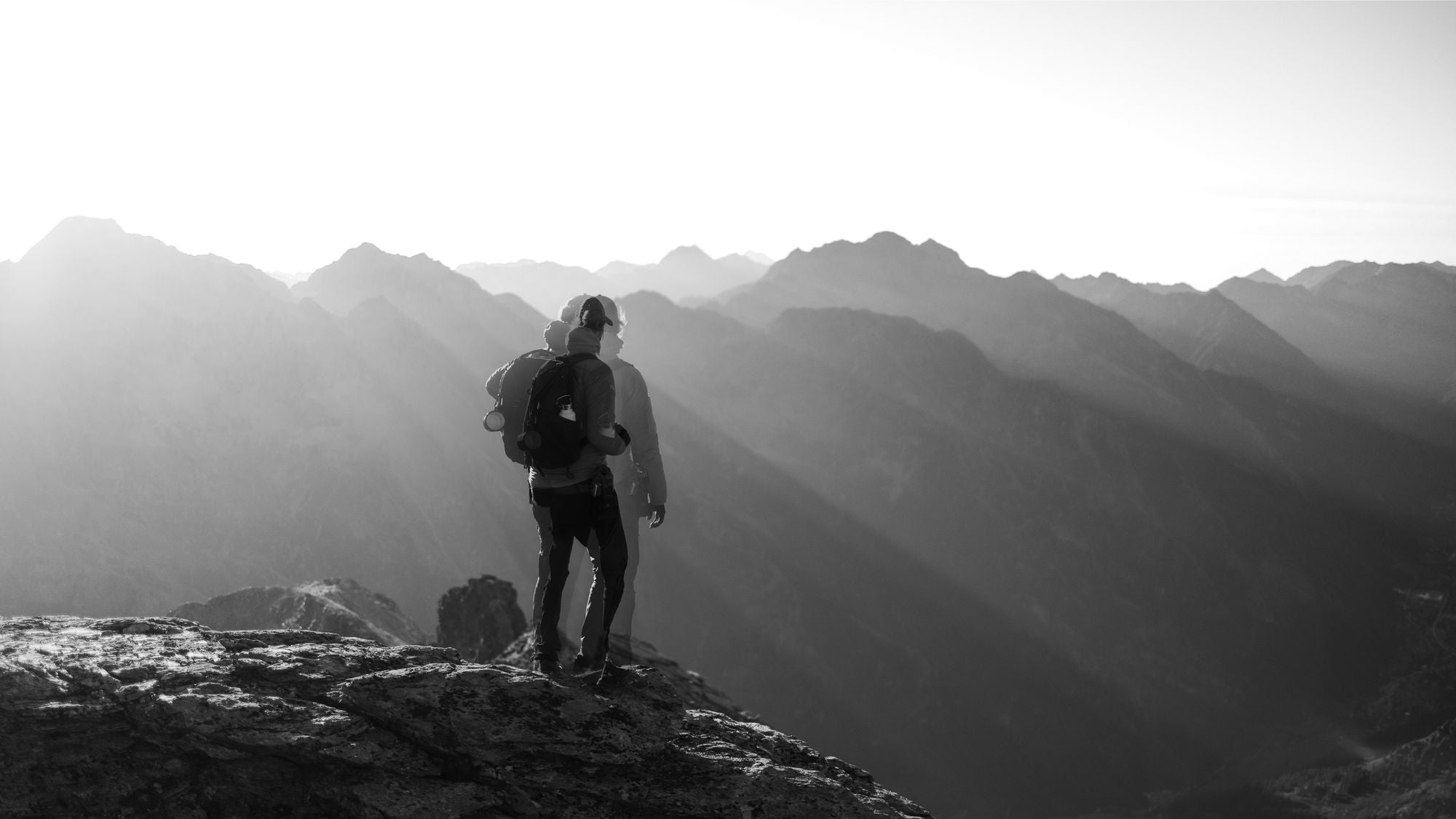 Solo hiker standing at a mountain summit during sunrise