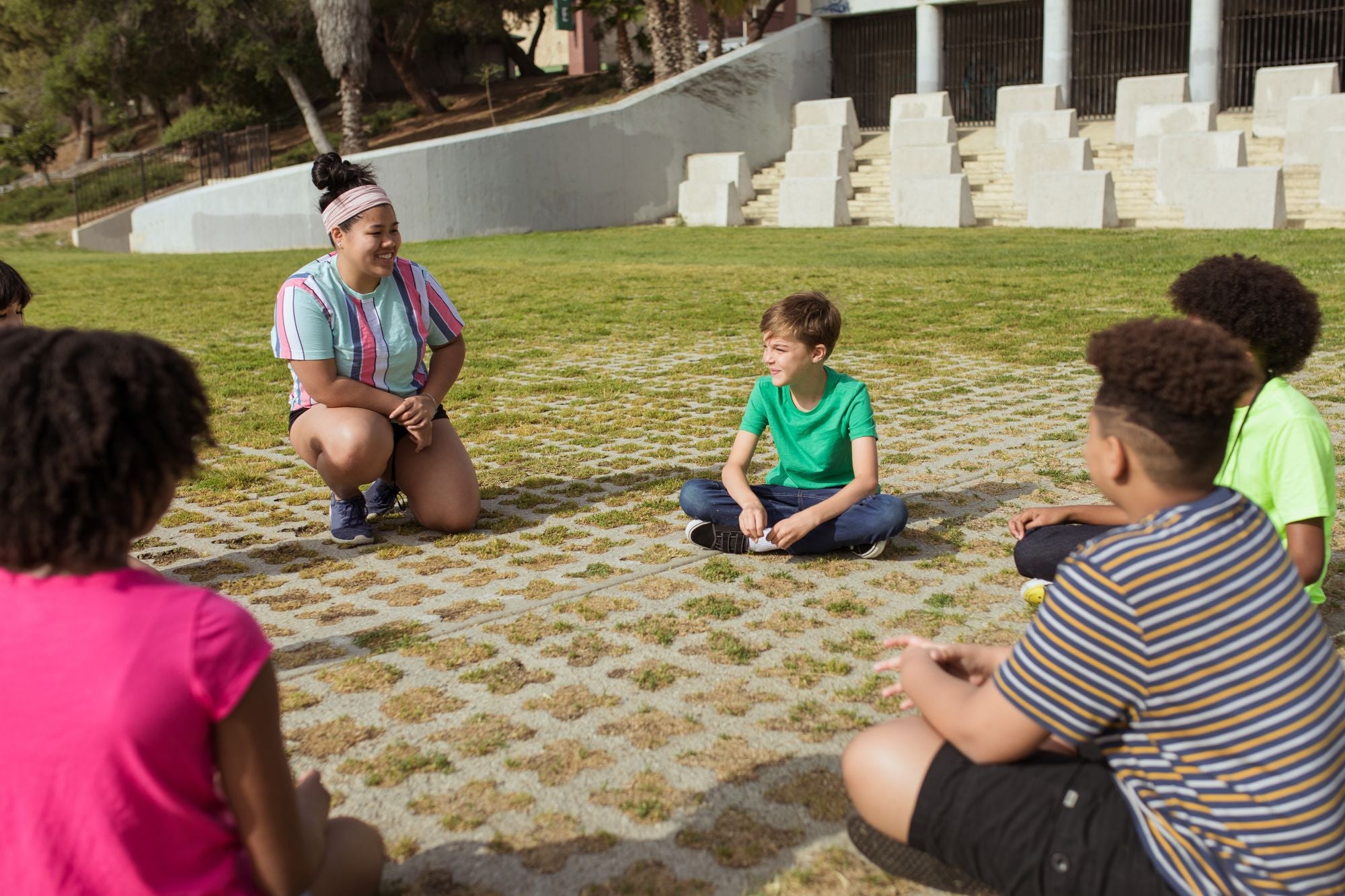 A diverse group of kids sitting in a circle outdoors