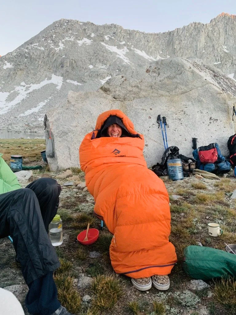 Person laughing in a sleeping bag outdoors