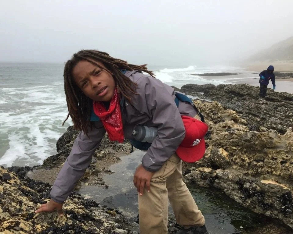 Young person exploring a rocky shoreline